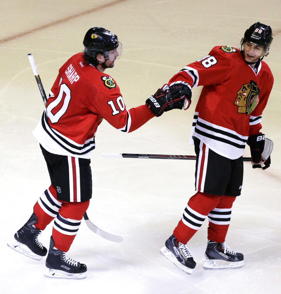 Chicago Blackhawks' Patrick Sharp (10), left, celebrates with teammate Patrick Kane (88) after scoring a goal during the third period in Game 6 of a first-round NHL hockey playoff series against St. Louis Blues in Chicago, Sunday, April 27, 2014. The Blackhawks won 5-1. (AP Photo/Nam Y. Huh)