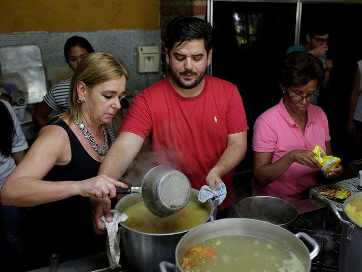 Diego Prada (C), Maria Luisa Pombo (L) and other volunteers of the Make The Difference (Haz La Diferencia) charity initiative prepare soup to be donated, at Maria Luisa's kitchen in Caracas, Venezuela March12, 2017. Picture taken March 12, 2017. REUTERS/Marco Bello