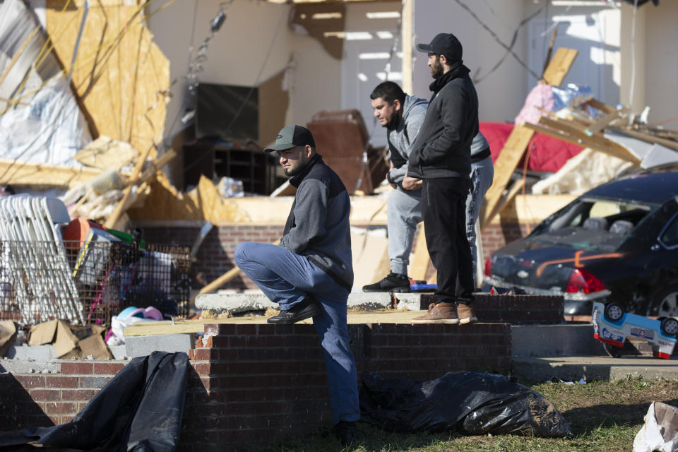 Jose Rivas, left, looks at tornado damage Tuesday, Dec. 14, 2021, in Bowling Green, Ky. Rivas has neighbors among those killed when a tornado slammed through the neighborhood the previous weekend. Entire families were lost, between them seven children, two of them infants. (AP Photo/James Kenney)