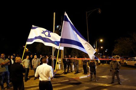 Israelis wave national flags next to security personnel securing an area in Jerusalem where a far-right activist was shot and wounded, October 29, 2014. REUTERS/ Ronen Zvulun