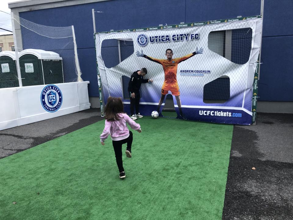 Mollie Reeves, 5, of Clinton, takes a shot on goal at the Subaru World Championship Village on April 11, 2024 while Utica City Football Club player Gordy Gurson helps her play. Mollie plays both soccer and ice hockey. The village was set up for the International Ice Hockey Federation World Championship in Utica.