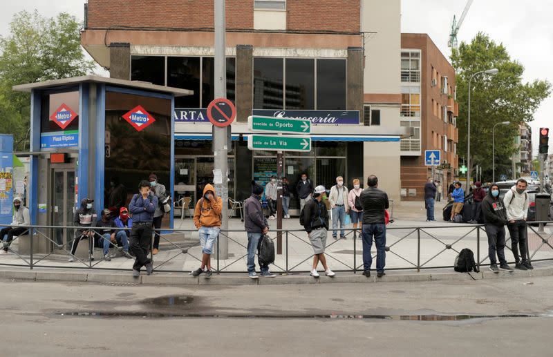 People wearing protective face masks stand at Usera neighbourhood in Madrid