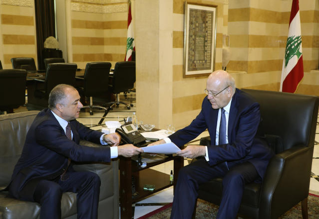 In this photo released by Lebanon's official government photographer Dalati Nohra, Lebanese Prime Minister Najib Makati, right, receives the final draft of the maritime border agreement between Lebanon and Israel from his deputy Elias Bou Saab who leads the Lebanese negotiating team, in Beirut, Lebanon, Tuesday, Oct. 11, 2022. Israel's prime minister said Tuesday that the country has reached an "historic agreement" with neighboring Lebanon over their shared maritime border after months of U.S.-brokered negotiations. (Dalati Nohra via AP)
