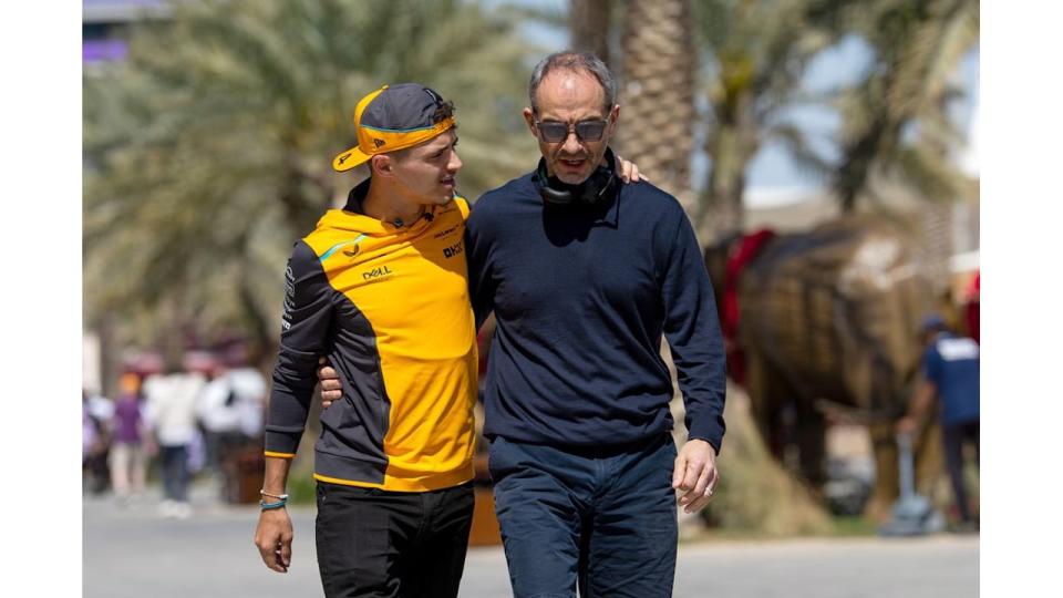 Lando Norris in an orange outfit wuth his arm around his father