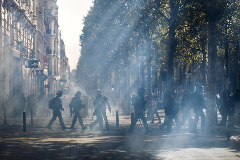 French riot police walk through a tear gas cloud on the Champs Elysees during a yellow vest demonstration, in Paris, Saturday, Sept 21. 2019. Paris police have used tear gas to disperse anti-government demonstrators who try to revive the yellow vest movement in protest at perceived economic injustice and French President Emmanuel Macron's government. The French capital was placed under high alert as few hundred anti-government protesters started marching in the Paris streets. (AP Photo/Kamil Zihnioglu)