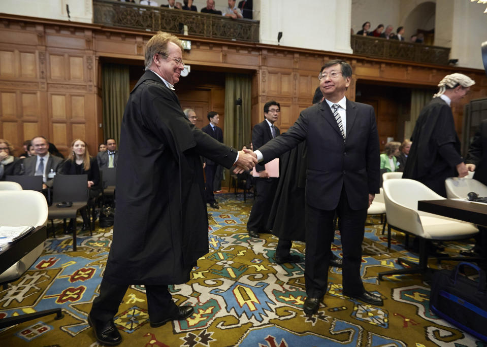 Japanese Ambassador to the Netherlands, and Chief Negotiator, Koji Tsuruoka, center, shakes hand with General Counsel of Australia Bill Campbell, left, before the International Court of Justice to deliver its verdict in The Hague, Netherlands, Monday March 31, 2014. The International Court of Justice is ruling Monday on Australia's challenge against Japan for whaling in Antarctic waters. (AP Photo/Phil Nijhuis)