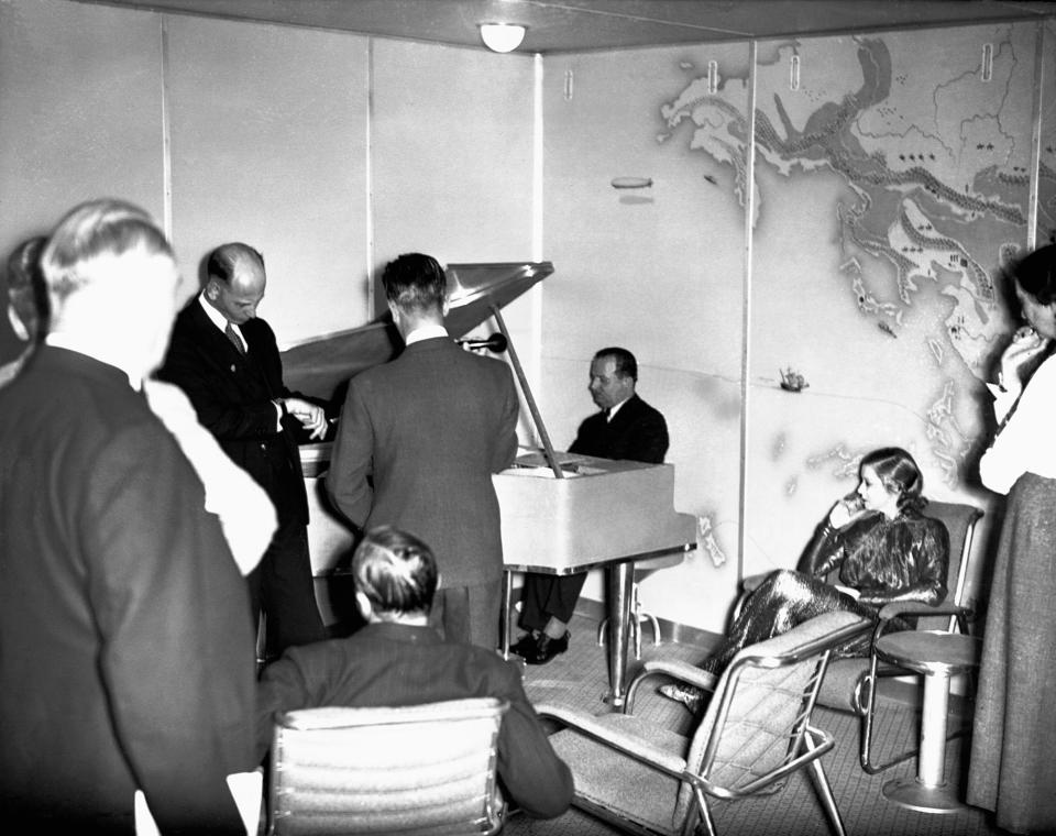 <p>Passengers gather around the piano in the lounge of the Hindenburg. (Corbis via Getty Images) </p>