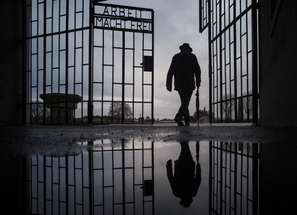 A man walks through the gate of the Sachsenhausen Nazi death camp with the phrase 'Arbeit macht frei' (work sets you free) at the International Holocaust Remembrance Day, in Oranienburg, about 30 kilometers, (18 miles) north of Berlin, Germany, Sunday, Jan. 27, 2019. The International Holocaust Remembrance Day marks the liberation of the Auschwitz Nazi death camp on Jan. 27, 1945. (AP Photo/Markus Schreiber)