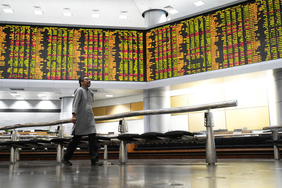 An Investor walks in front of stock trading boards at a private stock market gallery in Kuala Lumpur, Malaysia, Friday, Nov. 30, 2018. Share prices were mixed Friday in Asia ahead of the planned meeting by Presidents Donald Trump of the U.S. and Xi Jinping of China at the Group of 20 summit this weekend. (AP Photo/Yam G-Jun)