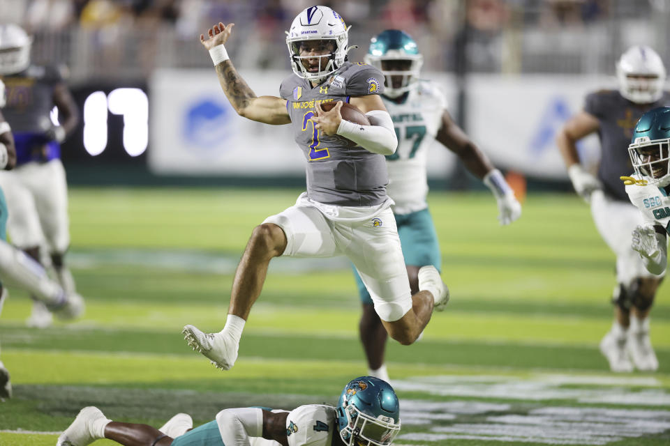 San Jose State quarterback Chevan Cordeiro (2) leaps over Coastal Carolina safety Tobias Fletcher (4) during the second half of the Hawaii Bowl NCAA college football game Saturday, Dec. 23, 2023, in Honolulu. (AP Photo/Marco Garcia)