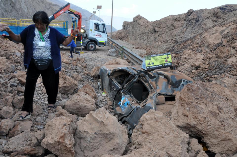 Una persona camina entre los restos de un deslizamiento de tierra provocado por un terremoto que bloqueó un camino en Iquique, en Chile, el miércoles 2 de abril de 2014. La suspensión el miércoles de la alerta de tsunami que afectó las costas chilenas tras el terremoto de magnitud 8,2 ocurrido en el extremo norte del país, permitió el lento regreso a sus hogares de decenas de miles de personas que amanecieron al aire libre. (AP foto/Str)