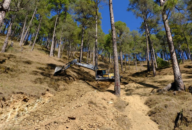 A worker uses a digger to build a path in the hill as part of an alternate plan to reach to the workers trapped in a tunnel after a portion of the tunnel collapsed in Uttarkashi