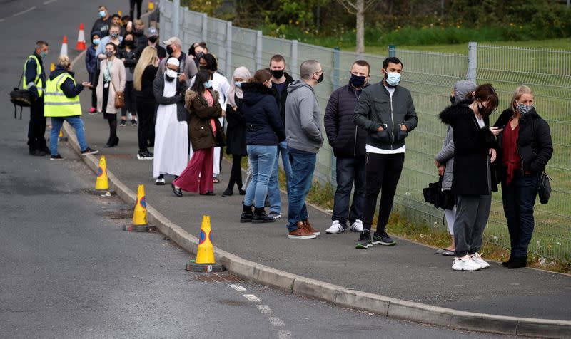 People line up outside a mobile vaccination centre, in Bolton