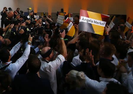 People hold placards while waiting for Christian Democratic Union CDU party leader and German Chancellor Angela Merkel to react on first exit polls in the German general election (Bundestagswahl) in Berlin, Germany, September 24, 2017. REUTERS/Fabrizio Bensch