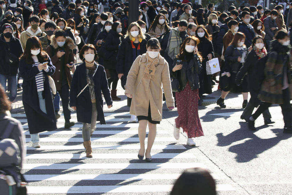 Decenas de personas con mascarillas para frenar la propagación del coronavirus cruzan una intersección concurrida del distrito comercial de Shibuya, en Tokio, el sábado 26 de diciembre de 2020. (Kyodo News vía AP)