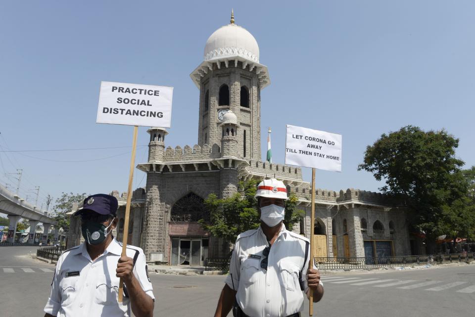 Traffic police personnel hold placards on a deserted road during a one-day nationwide Janata (civil) curfew imposed as a preventive measure against the COVID-19 coronavirus, in Hyderabad on March 22, 2020. - Nearly one billion people around the world were confined to their homes, as the coronavirus death toll crossed 13,000 and factories were shut in worst-hit Italy after another single-day fatalities record. (Photo by NOAH SEELAM / AFP) (Photo by NOAH SEELAM/AFP via Getty Images)