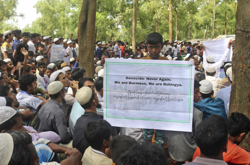 A Rohingya refugee boy holds a placard during a gathering to mark the fifth anniversary of their exodus from Myanmar to Bangladesh, at a Kutupalong Rohingya refugee camp at Ukhiya in Cox's Bazar district, Bangladesh, Thursday, Aug. 25, 2022. Hundreds of thousands of Rohingya refugees on Thursday marked the fifth anniversary of their exodus from Myanmar to Bangladesh, while the United States, European Union and other Western nations pledged to continue supporting the refugees' pursuit of justice in international courts.(AP Photo/ Shafiqur Rahman)