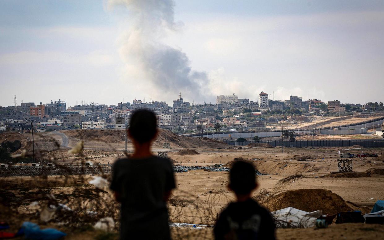 Boys watch smoke billowing during Israeli strikes east of Rafah in the southern Gaza Strip