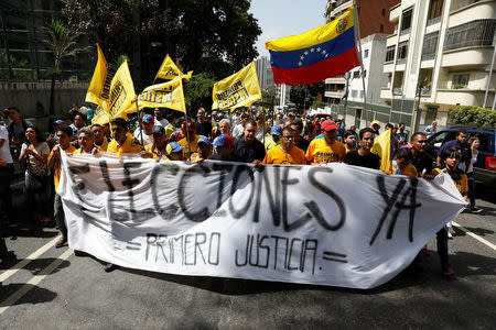 Demonstrators carry a banner reading "Elections now, justice first" during an opposition rally in Caracas, Venezuela April 4, 2017. REUTERS/Carlos Garcia Rawlins