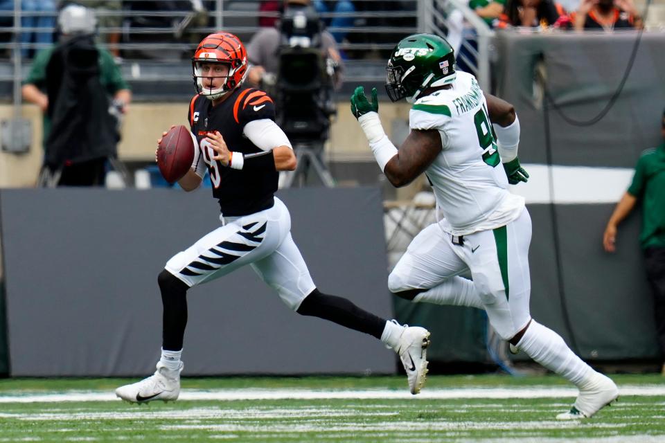 Cincinnati Bengals quarterback Joe Burrow (9) scrambles away from New York Jets defensive end John Franklin-Myers (91) in the first quarter.