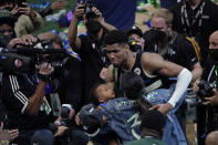 Milwaukee Bucks forward Giannis Antetokounmpo hugs his girlfriend Mariah Riddlesprigger and son Liam after defeating the Phoenix Suns in Game 6 of basketball's NBA Finals Tuesday, July 20, 2021, in Milwaukee. The Bucks won 105-98. (AP Photo/Aaron Gash)