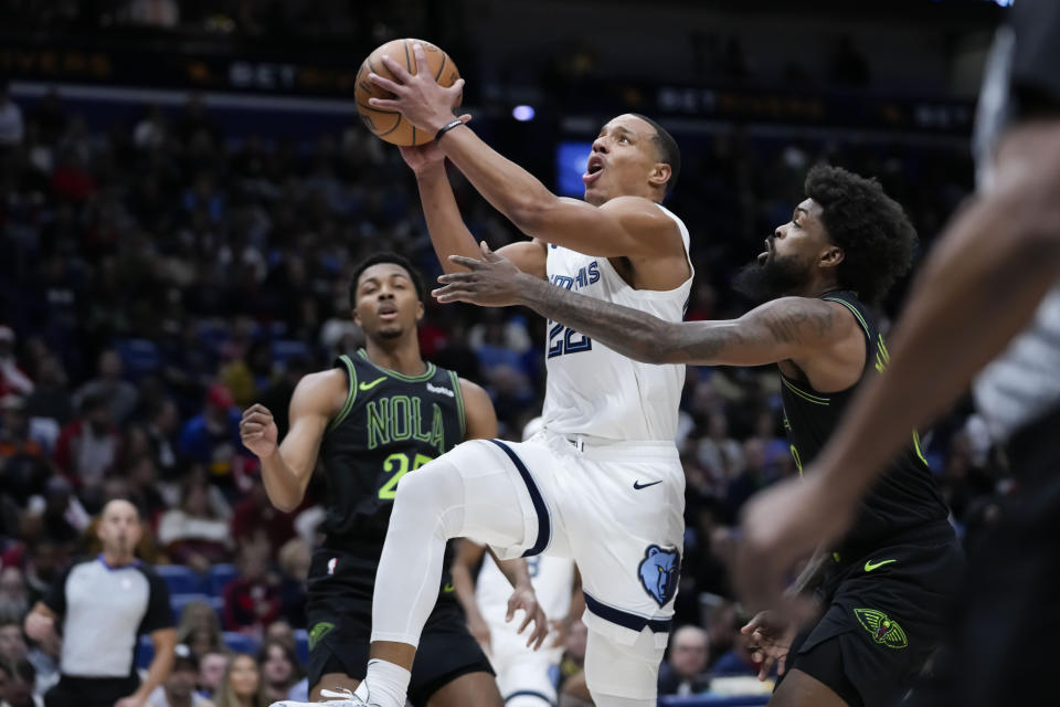 Memphis Grizzlies guard Desmond Bane (22) drives to the basket between New Orleans Pelicans forward Naji Marshall and guard Trey Murphy III (25) in the first half of an NBA basketball game in New Orleans, Tuesday, Dec. 19, 2023. (AP Photo/Gerald Herbert)