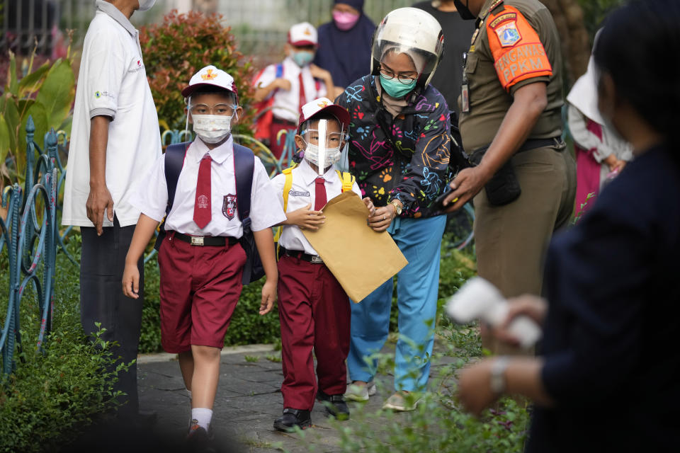 Students wearing face masks to prevent the spread of COVID-19 arrive on the first day of school reopening at an elementary school in Jakarta, Indonesia, Monday, Aug. 30, 2021. Authorities in Indonesia's capital kicked off the school reopening after over a year of remote learning on Monday as the daily count of new COVID-19 cases continues to decline. (AP Photo/Dita Alangkara)