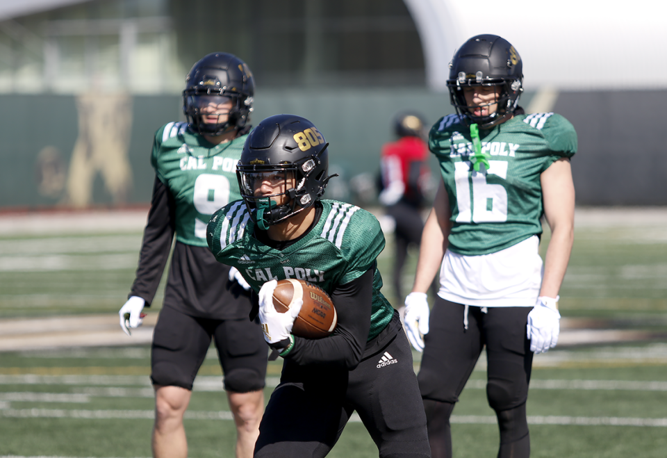 From left, Evan Burkhart (9), Michael Briscoe (10) and Logan Booher (16) conduct drills during the Cal Poly football team’s spring practices at Doerr Family Field on April 14, 2023.