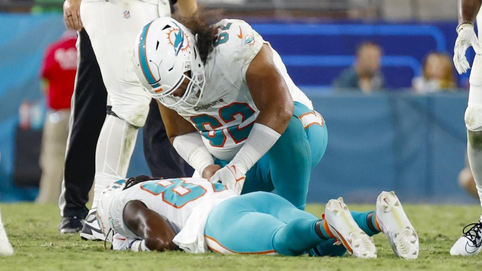 Miami Dolphins center Alama Uluave (62) checks on injured wide receiver Daewood Davis (87) after Davis was hit by Jacksonville Jaguars linebacker Dequan Jackson and cornerback Kaleb Hayes in the fourth quarter of an NFL football preseason game in Jacksonville, Fla., Saturday, Aug. 26, 2023. (Al Diaz/Miami Herald via AP)