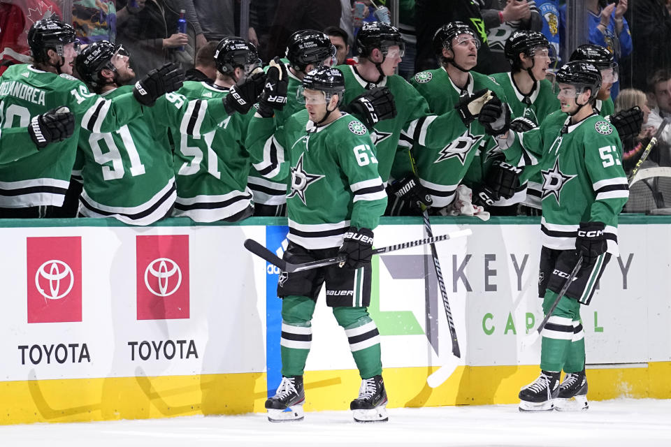 Dallas Stars right wing Evgenii Dadonov (63) and center Wyatt Johnston (53) celebrate with the bench after Dadonov scored in the second period of an NHL hockey game against the Vancouver Canucks, Monday, Feb. 27, 2023, in Dallas. Johnston and Ryan Suter were credited with the asssits on the score. (AP Photo/Tony Gutierrez)