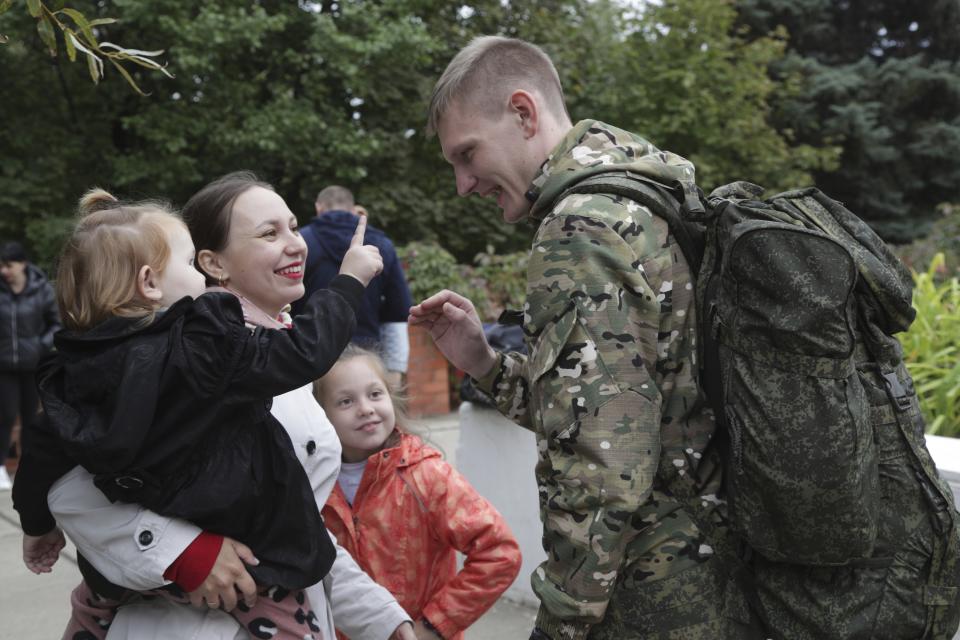 FILE - A Russian recruit speaks to his wife and children outside a military recruitment center in Volzhskiy, Volgograd region, Russia, Sept. 28, 2022. Since Russian President Vladimir Putin announced his mobilization on Sept. 21 for the war in Ukraine, independent media, human rights activists and draftees themselves have painted a bleak picture of a haphazard, chaotic and ethnically biased effort to round up as many men as possible and push them quickly to the front, regardless of skill or training. (AP Photo/File)