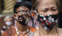 A devotee wearing a protective mask bearing the face of Jesus Christ waits outside the Minor Basilica of the Black Nazarene, popularly known as Quiapo church, as it slowly reopens its doors in downtown Manila, Philippines on Friday, June 5, 2020. President Rodrigo Duterte has expressed relief that "Filipinos are really law-abiding" and that the Philippines was not going through riots like America which would make coronavirus quarantine enforcement formidable. (AP Photo/Aaron Favila)