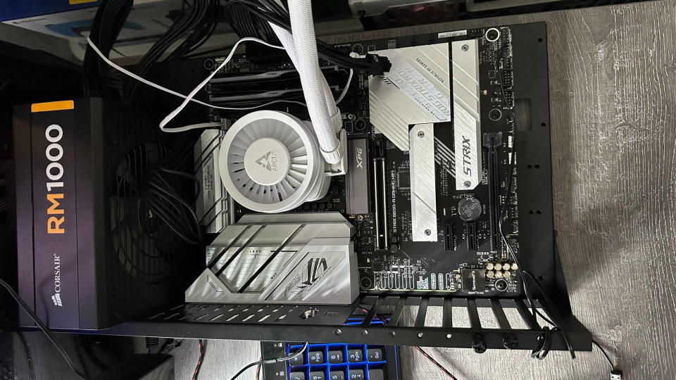 A photo of an open case, test bench PC showing the motherboard, PSU and CPU cooler