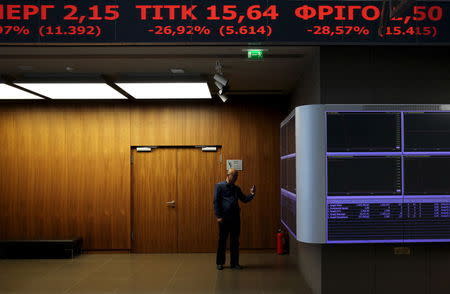 A journalist takes pictures of the electronic boards displaying stock prices in the reception hall in Athens stock exchange, Greece August 3, 2015. REUTERS/Yiannis Kourtoglou