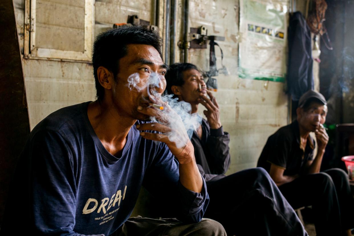 Tobacco farmer Guo Jian takes a smoke break after a day working at a tobacco leaf factory in the mountains of Yunnan, China.