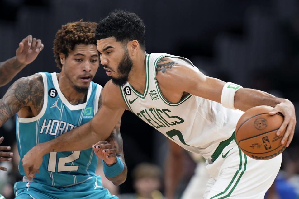 Charlotte Hornets' Kelly Oubre Jr., left, tries to defend as Boston Celtics' Jayson Tatum, right, drives toward the basket in the first half of a preseason NBA basketball game against the Charlotte Hornets, Sunday, Oct. 2, 2022, in Boston. (AP Photo/Steven Senne)