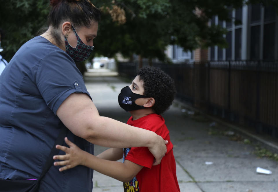 Christina Mendez leans down to hug her 7-year-old son, Elidios Kenel, after meeting with dozens of other concerned parents and students at St. Francis Xavier School in Newark, Thursday, Aug. 6, 2020. The Archdiocese of Newark announced the school's permanent closure the previous week. (AP Photo/Jessie Wardarski)