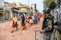 Muslim people, that visited the capital for a wedding, walk past security personnel patrolling near burnt-out and damaged residential premises following clashes between people supporting and opposing a contentious amendment to India's citizenship law, in New Delhi on February 26, 2020. - Riot police patrolled the streets of India's capital on February 26 and the city's leader called for a curfew following battles between Hindus and Muslims that claimed at least 20 lives. (Photo by Sajjad HUSSAIN / AFP) (Photo by SAJJAD HUSSAIN/AFP via Getty Images)