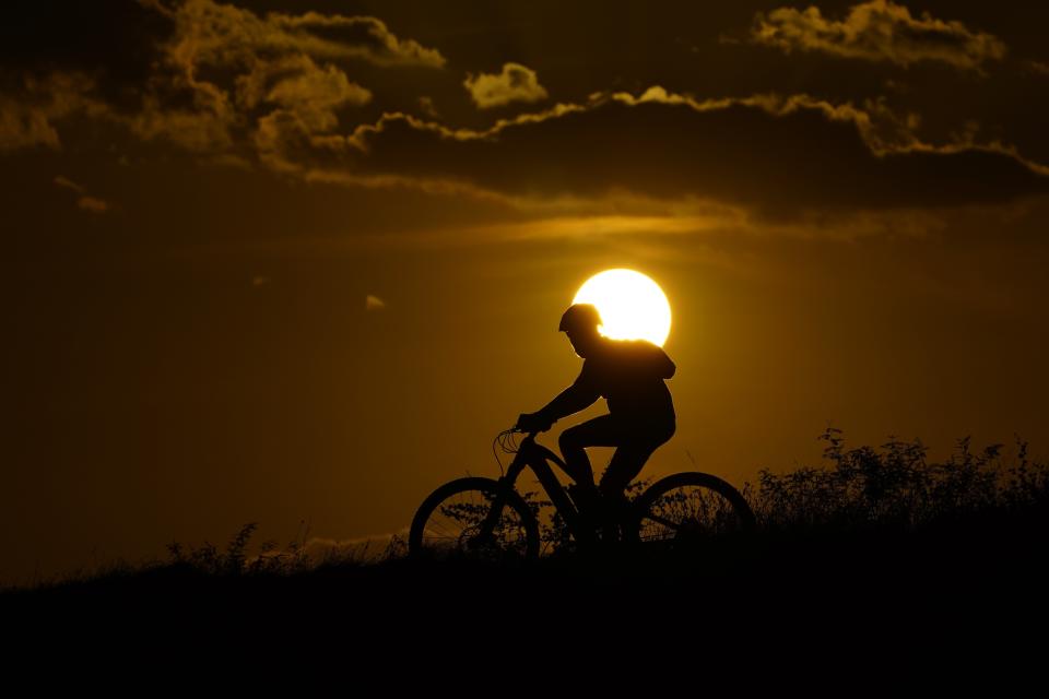 FILE - A cyclist tops a hill on a hot day at sunset, Aug. 20, 2023, in San Antonio. UN weather agency says Earth sweltered through the hottest summer ever as record heat in August capped a brutal, deadly three months in northern hemisphere. (AP Photo/Eric Gay, File)