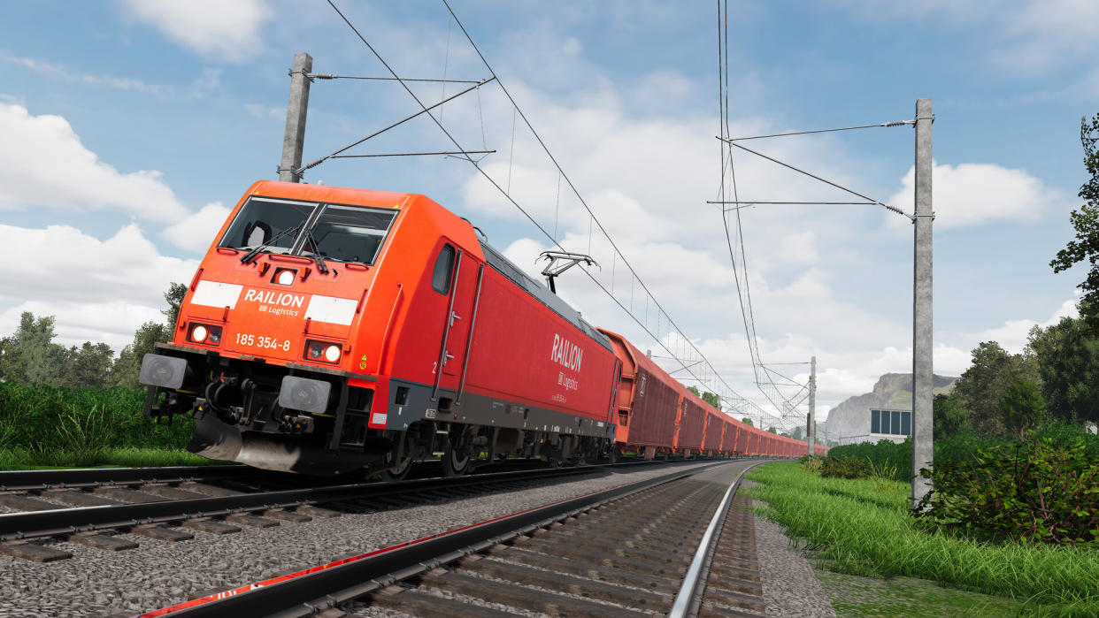  A red train going past on a sunny day. 