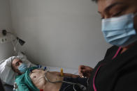 A nurse examines a patient ar the hospital for the homeless in Budapest, Hungary, Wednesday, April 14, 2021. A bitter conflict has emerged between Hungary’s right-wing government and the liberal leadership of the country's capital city over a hospital for the homeless that may soon have to close. The Budapest hospital provides medical and social services and shelter to more than 1,000 people annually. But the Hungarian government has ordered it to vacate the state-owned building it occupies. Budapest's mayor says the eviction will risk the lives of the hospital's homeless patients as Hungary struggles with a deadly COVID-19 surge. (AP Photo/Laszlo Balogh)