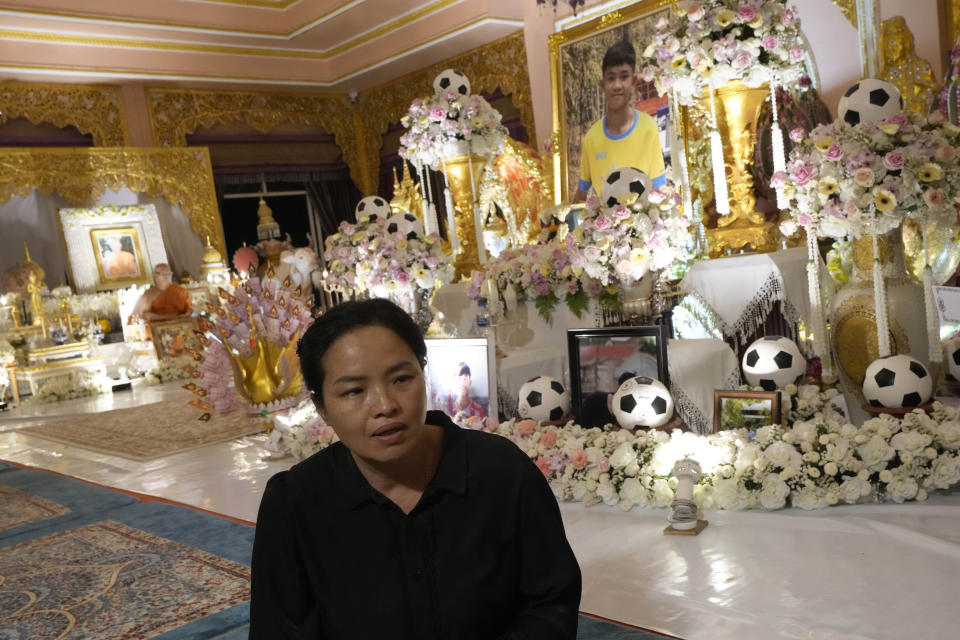 Thanaporn Phromthep talks to a reporter in front of the ashes of her son Duangphet Phromthep at Wat Phra That Doi Wao temple in Chiang Rai province Thailand, Saturday, March 4, 2023. The cremated ashes of Duangphet, one of the 12 boys rescued from a flooded cave in 2018, arrived in the far northern Thai province of Chiang Rai on Saturday where final Buddhist rites for his funeral will be held over the next few days following his death in the U.K. (AP Photo/Sakchai Lalit)