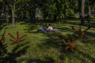 People sit in a park next anti-tank hedgehogs in Kyiv, Saturday, May 6, 2023. (AP Photo/Bernat Armangue)