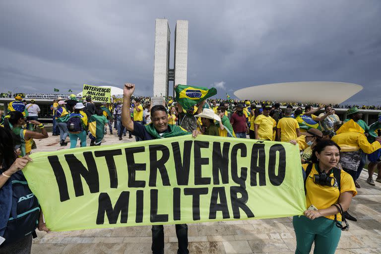 Seguidores del ex Presidente Jair Bolsonaro sostienen un cartel que dice "Intervención Civil y Militar!".