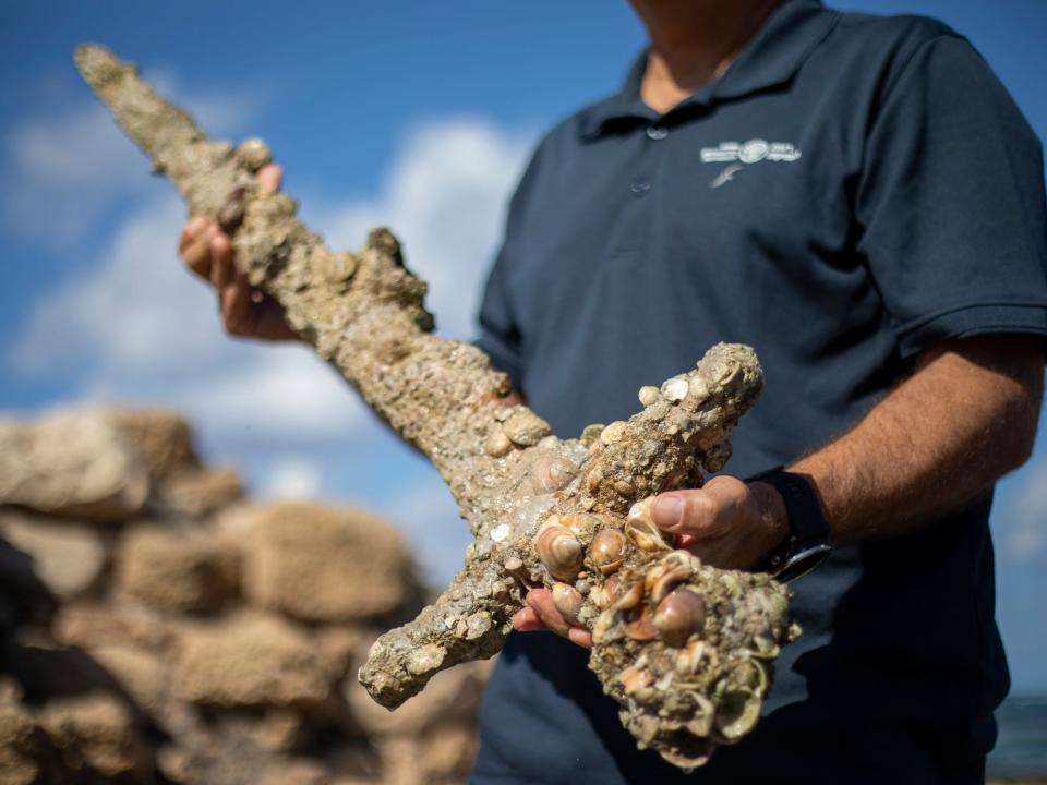 Jacob Sharvit, director of the Marine Archaeology Unit of the Israel Antiquities Authority, holds a meter-long (yard-long) sword, that experts say dates back to the Crusaders, in the Mediterranean seaport of Cesarea, Israel, Tuesday, Oct. 19, 2021.