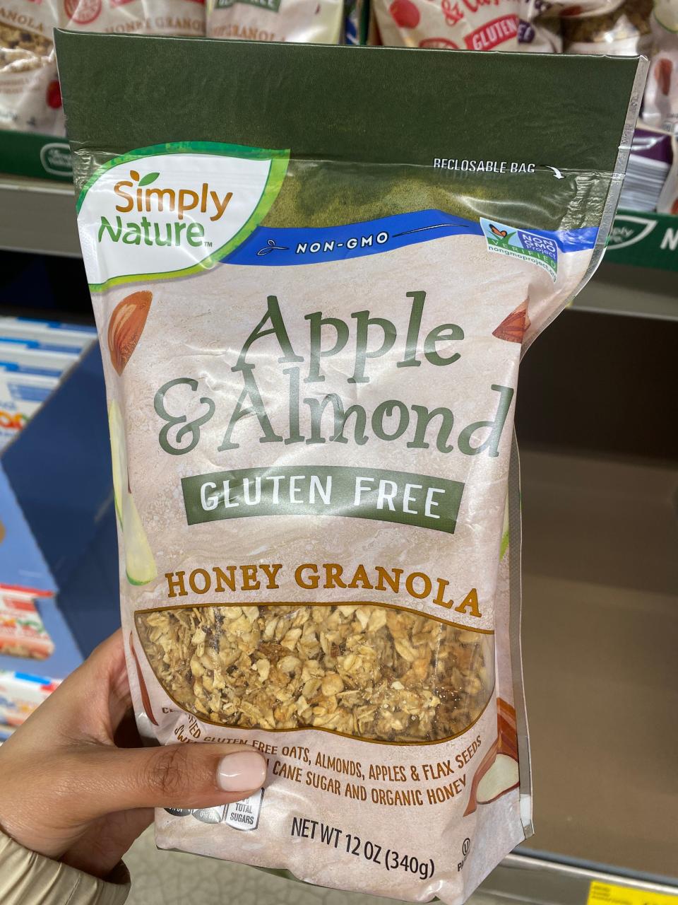 Hand holding beige bag of honey granola at Aldi