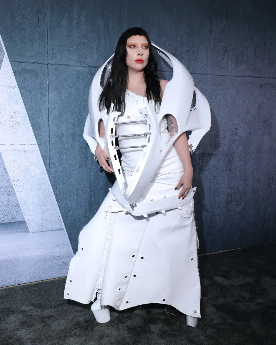 Lady Gaga wears a futuristic white dress with structural, armor-like elements at an event