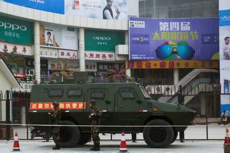 FILE PHOTO: Security personel stand in front of an armoured vehicle in Kashgar, Xinjiang Uighur Autonomous Region, China, March 24, 2017. REUTERS/Thomas Peter/File Photo