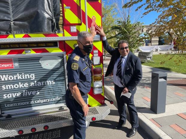 Calgary Mayor Naheed Nenshi and Calgary Fire Department Chief Steve Dongworth pose to show the new orange ribbon decals that will be placed on all city vehicles to show the city's commitment to remembrance, truth and reconciliation with Indigenous people. (Scott Dippel/CBC - image credit)