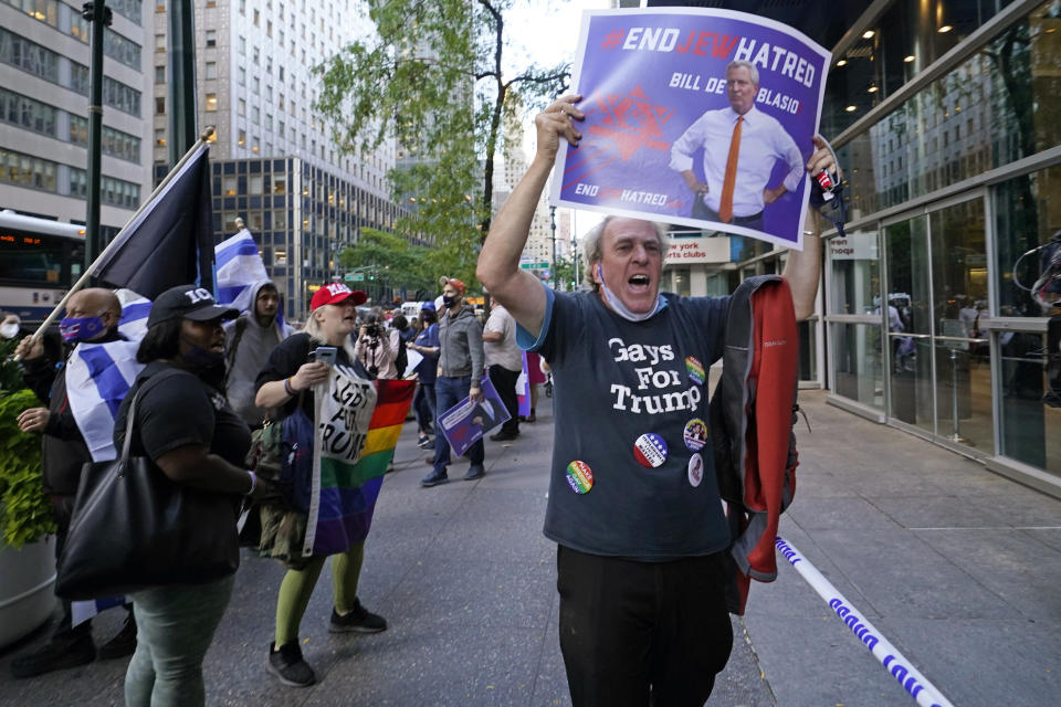A Trump and gay rights supporter joins a group of people protesting discrimination against Jewish people outside the offices of New York Gov. Andrew Cuomo, Thursday, Oct. 15, 2020, in New York. Cuomo ordered schools to close in some Orthodox Jewish communities and other New York city and upstate communities where there have been recent spikes in coronavirus levels, angering members of those communities. (AP Photo/Kathy Willens)